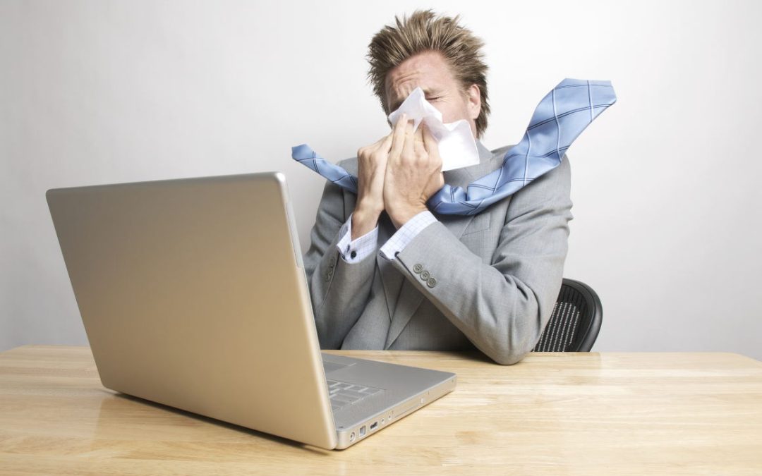 man sneezing at desk