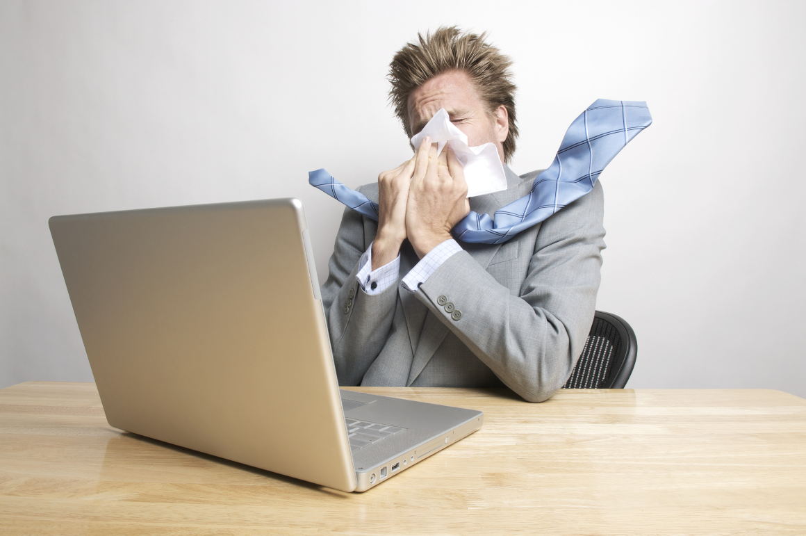 man-sneezing-at-desk man sneezing at desk