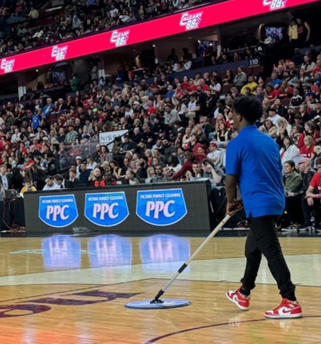 PPC staff cleaning the basketball court during a Calgary Surge game, with Picture Perfect Cleaning logos on the LED boards.