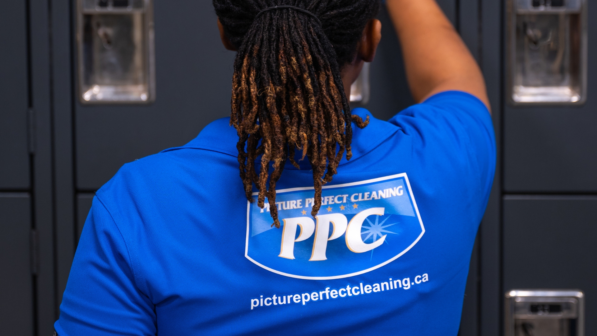 Janitorial Staff Cleaning Lockers – Picture Perfect Cleaning Picture Perfect Cleaning team member wearing blue uniform and gloves, disinfecting lockers in a commercial facility in Calgary or Edmonton.