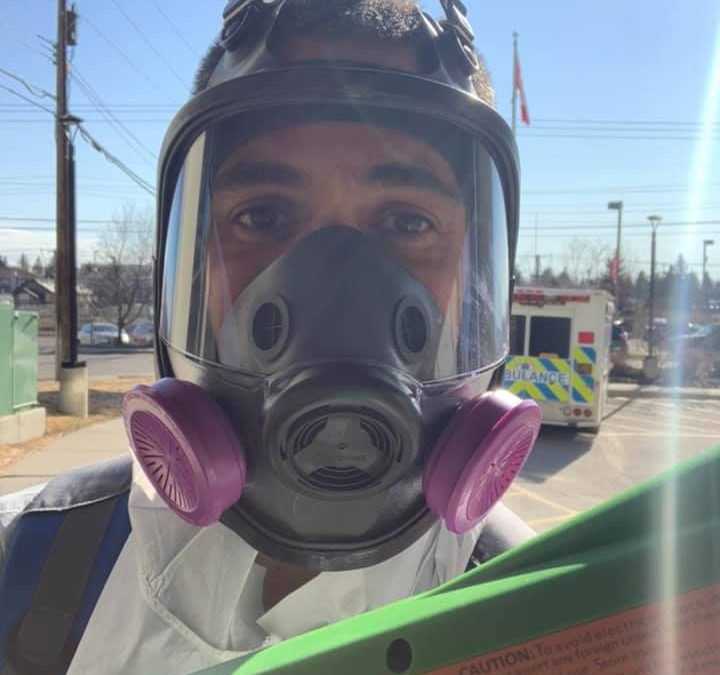 A Picture Perfect Cleaning technician wearing a full-face respirator and protective suit while using an electrostatic disinfectant sprayer during COVID-19 sanitation protocols.