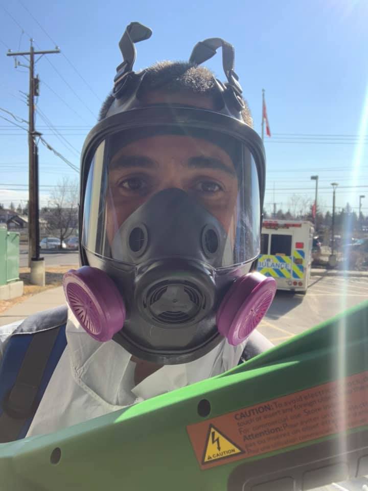 A Picture Perfect Cleaning technician wearing a full-face respirator and protective suit while using an electrostatic disinfectant sprayer during COVID-19 sanitation protocols.