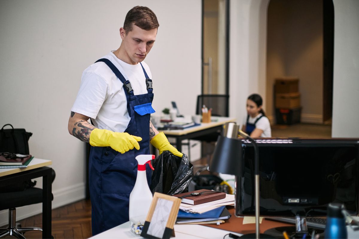 Two professional cleaners in white tshirts and blue overalls clean an office building.